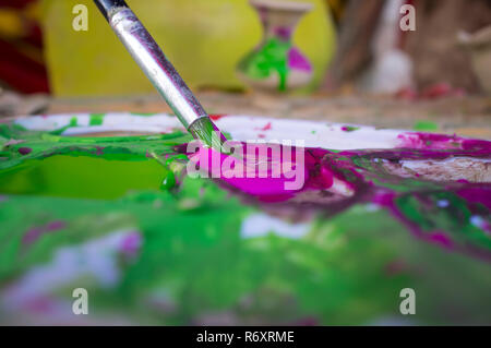 Caricamento del bambino con il colore viola il suo pennello Foto Stock