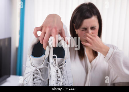 Donna che mantiene sporchi scarpe maleodoranti Foto Stock