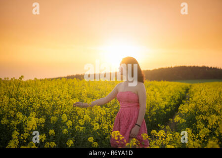 La donna in un campo di colza al tramonto Foto Stock