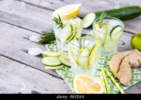 Limonata fatta in casa con calce, rosmarino, Zenzero, cetriolo e di ghiaccio su un sfondo di legno Foto Stock