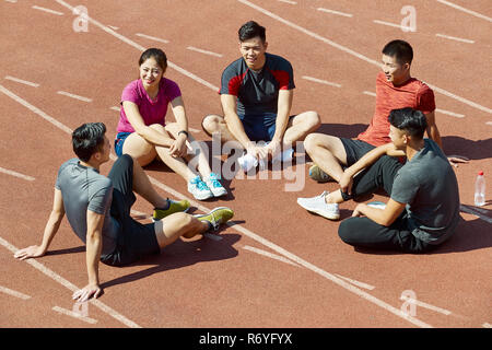 Un gruppo di giovani atleti asiatici parlando e rilassante sulla via dopo il training. Foto Stock