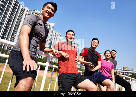 Gruppo di felice giovani atleti asiatici rilassante dopo la formazione. Foto Stock