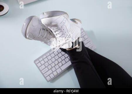 Imprenditrice attraversato gamba sulla tastiera del computer Foto Stock