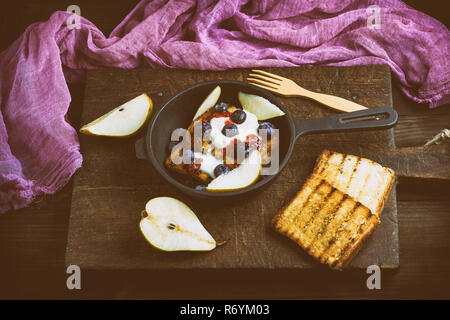 Toast alla francese con frutti di bosco, sciroppo e panna acida in un nero ghisa padella Foto Stock