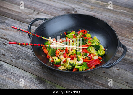 Wok con verdure e bacchette sul terreno in legno Foto Stock