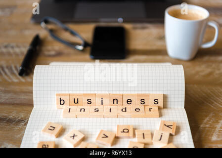 Primo piano su notebook su tavola di legno sfondo, concentrarsi sui blocchi di legno con lettere rendendo il processo di Business Insider parole Foto Stock