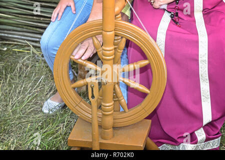 In legno antico ruote di filatura e di una donna in costume nazionale. Foto Stock