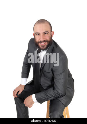 Business uomo seduto, la flessione in avanti, sorridente Foto Stock