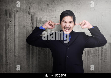 Sottolineato asian business man collegando le sue orecchie con le dita Foto Stock