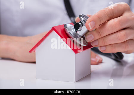 Donna che utilizza uno stetoscopio per controllare il modello di casa Foto Stock