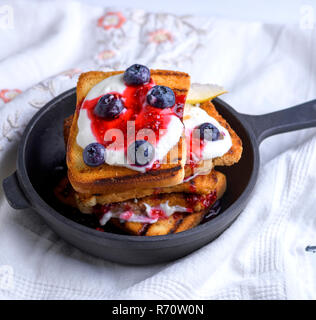 Toast alla francese con frutti di bosco, sciroppo e panna acida in un nero ghisa padella Foto Stock