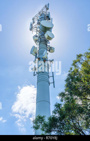 Montante di telecomunicazione con antenna TV e telefono mobile trasmettitore contro un cielo blu Foto Stock