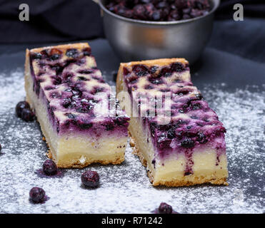 Pezzi di torta di ricotta e mirtilli su sfondo nero Foto Stock
