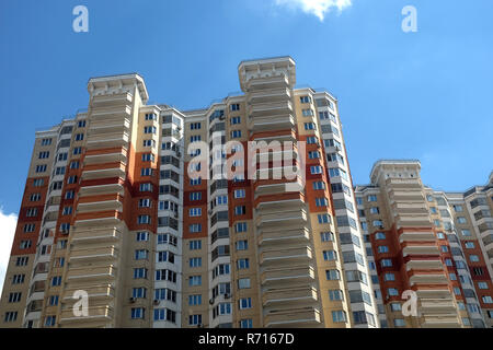 La sezione superiore del moderno appartamento edificio costruito da mattoni su chiaro cielo blu con nuvole bianche sul giorno di estate Foto Stock