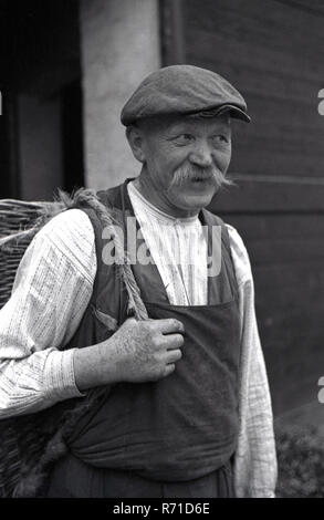 1930s, storico, pre-guerra, Sudentenland, Cecoslovacchia, un ritratto di una fattoria maschio operaio portando il suo cesto. Foto Stock