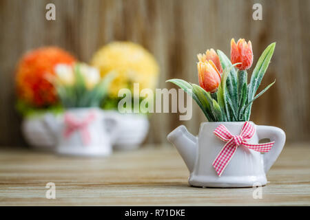 Tulipani artificiali in porcellana bianca Pots con teiera Design e nastro rosa Foto Stock