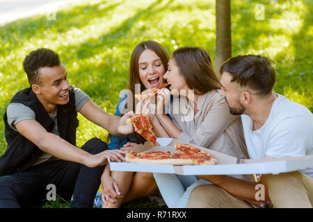 Amici prendendo fette di pizza Foto Stock