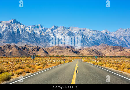 Empty road vicino al Lone Pine con rocce dell'Alabama Hills e la Sierra Nevada in background, Inyo County, California, Stati Uniti. Foto Stock