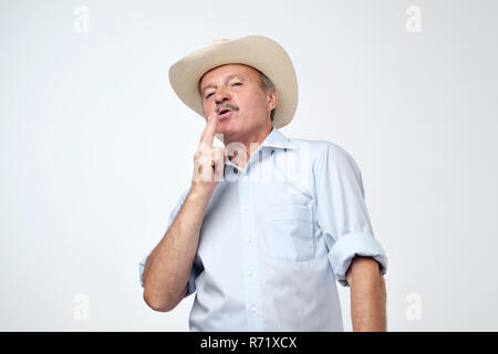 Senior uomo in cappello da cowboy fingendo che egli è il fumo Foto Stock