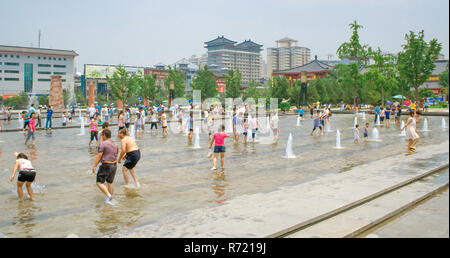 La popolazione locale e i turisti a giocare con l'acqua durante il periodo estivo nella fontana musicale, Dayan Pagoda Square, Xian, Cina. Foto Stock