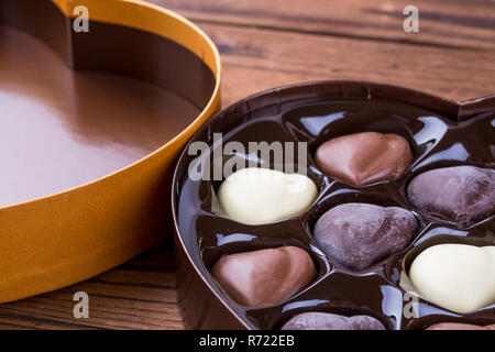 A forma di cuore con scatola a forma di cuore il buio e la luce tartufi di cioccolato su un tavolo di legno Foto Stock