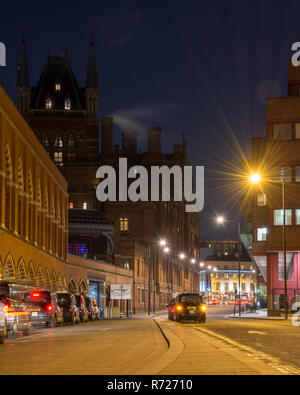 London, England, Regno Unito - 27 Febbraio 2018: i taxi coda in un rango al di fuori della Londra ornato gotico vittoriano mattone St Pancras Stazione Ferroviaria di notte. Foto Stock