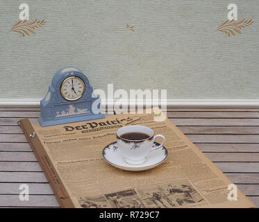 Inglese tazzina e piattino davanti ad un blu pallido Wedgwood watch, Jasperware, con applicata la piastra di sfiato di argilla bianca su un vecchio giornale tedesco Foto Stock