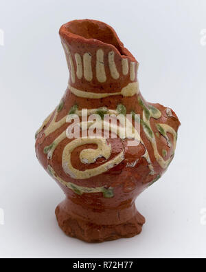 Brocca in ceramica utilizzato con fanghi decorazione sulla superficie di supporto, di piccole dimensioni, bricco per il supporto di stoviglie suolo trovare ceramica smalto terracotta smalto di piombo Ossido di rame, girato a mano decorato cotto smaltato anello della brocca sopra il piede ristretta pancia convessa di un orecchio leggermente svasato a collo rosso con giallo e verde di archeologia di limo Rotterdam tunnel ferroviario che serve cucina camera di cottura che serve olio rilevamento del suolo: tunnel ferroviario di Rotterdam. Foto Stock