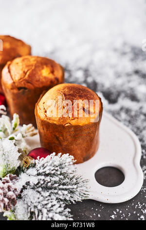 Mercatino di Natale di panettone con uvetta e frutta secca su bianco piatto con neve in background con copia spazio per il testo. Foto Stock