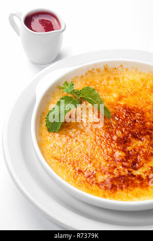 Francese dessert creme brulee con salsa di frutti di bosco e menta in una piastra bianca Foto Stock