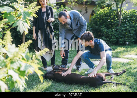 Coppia con figlio e cane in giardino Foto Stock