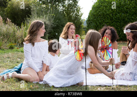 Amiche e familiari aventi picnic in giardino Foto Stock