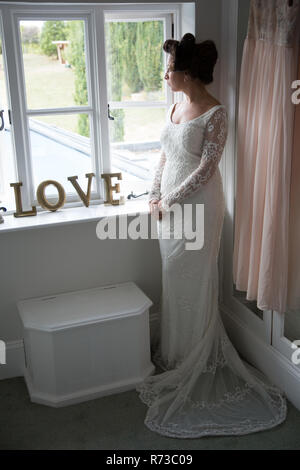 Sposa guardando fuori della finestra prima di nozze Foto Stock