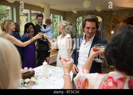 Gli ospiti dei matrimoni tostare per novelli sposi presso la reception Foto Stock