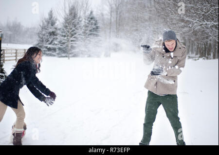Coppia giovane avente snowball lotta in coperta di neve la foresta, Ontario, Canada Foto Stock
