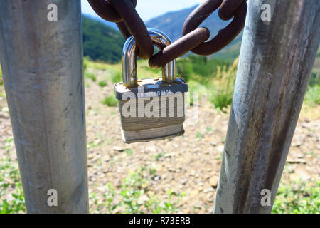 Una porta di metallo incatenati chiusa da un arrugginito catena e un lucchetto di grandi dimensioni. Foto Stock