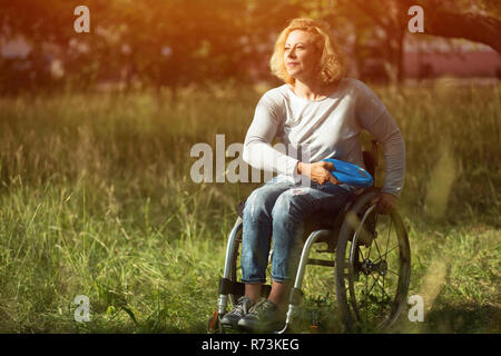 Donna in carrozzella getta frisbee Foto Stock