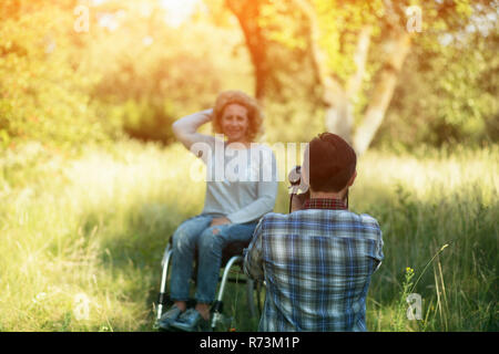 Professianl fotografo prende foto di donna in sedia a rotelle Foto Stock