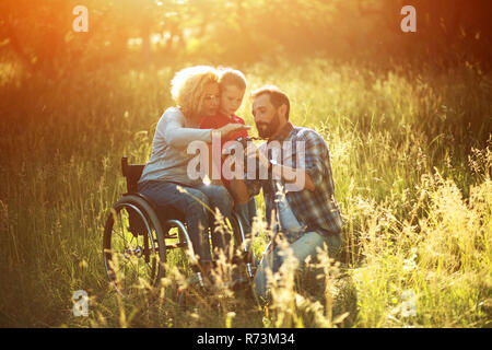 Fotografo scatta foto di famiglia felice dove la donna è in una sedia a rotelle Foto Stock