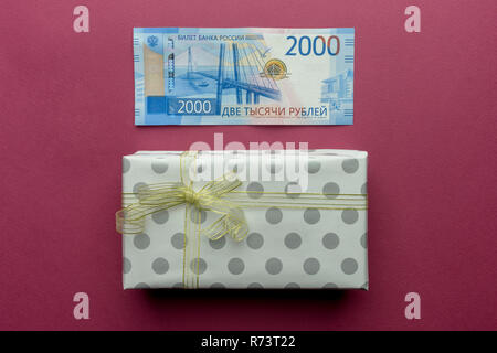 Due mila rublo russo di denaro con confezione regalo con oro bow isolato su sfondo viola. Posto per il testo Foto Stock