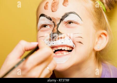 Madre di verniciatura di un volto di sua figlia come ragazza cat Foto Stock