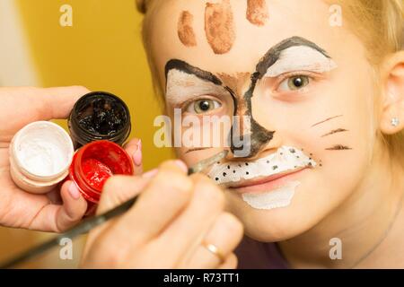 Madre di verniciatura di un volto di sua figlia come ragazza cat Foto Stock