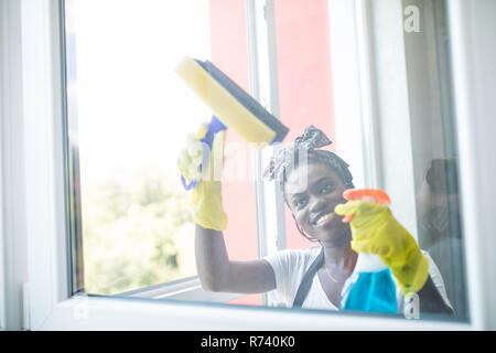 Sorridente afro american donna Pulizia vetro Vetro con ventosa Foto Stock