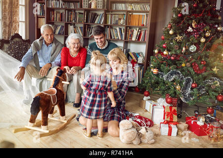 Allegro i genitori con i nonni e la bambina insieme per il tempo di Natale Foto Stock