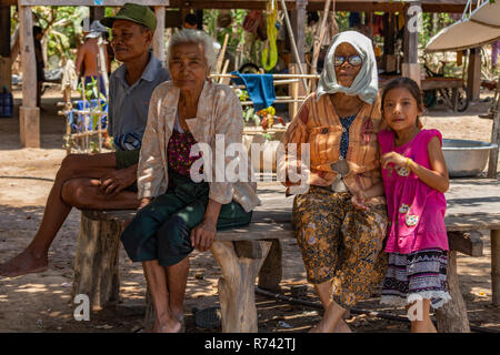 Don Daeng, Laos - Aprile 27, 2018: un gruppo di abitanti locali seduti su una panca in legno Foto Stock