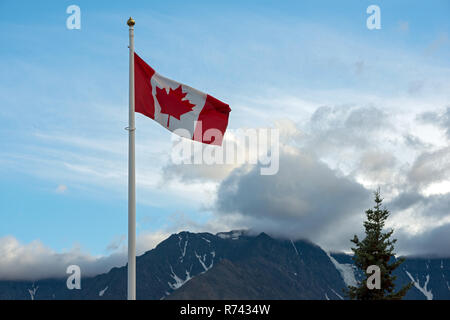 La bandiera canadese sorvolano picchi di montagna Foto Stock