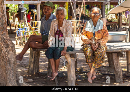 Don Daeng, Laos - Aprile 27, 2018: gruppo di anziani abitanti del villaggio seduto su una panca in legno Foto Stock