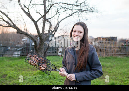 Giovane donna felice mangiare pollo shish kebab Foto Stock