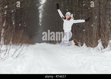 Atletica Giovane donna che si tuffa in una foresta in inverno. Bella ragazza impegnata nel fitness in winter park. Foto Stock