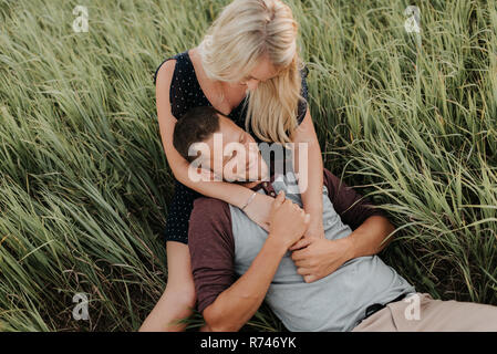 Romantico giovane donna e il mio ragazzo insieme reclinabili in campo di erba lunga Foto Stock